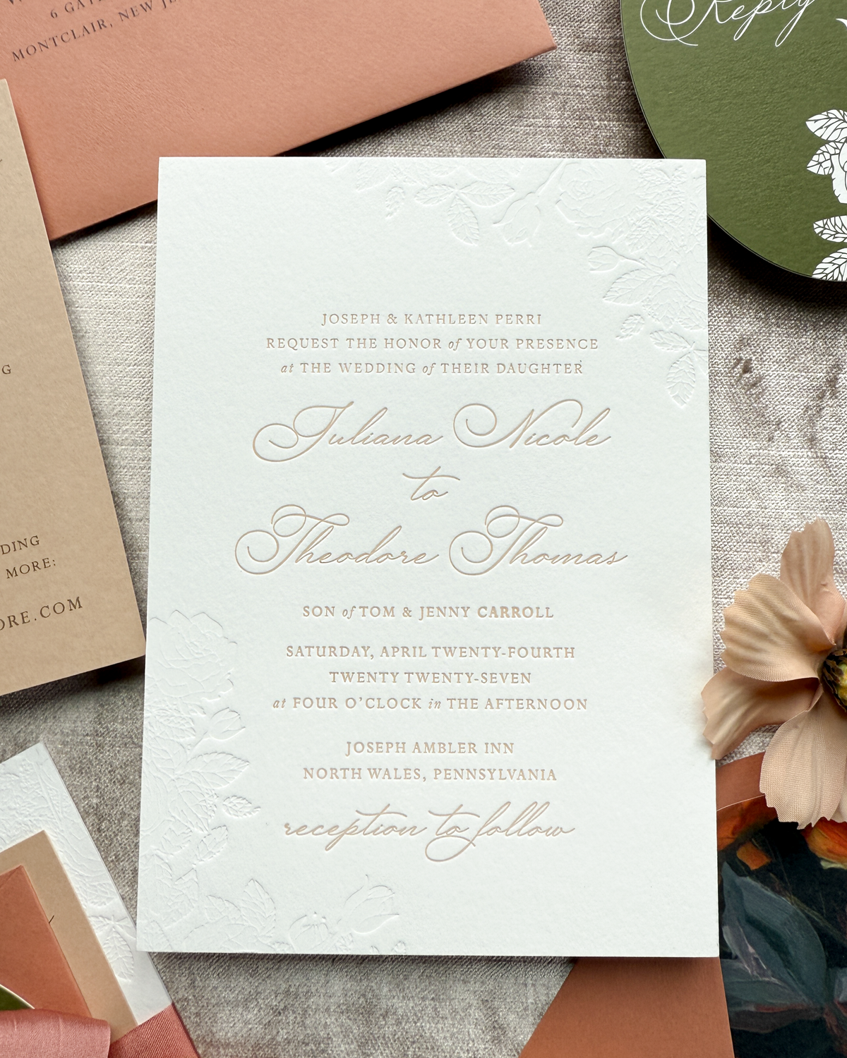 Wedding invitation card with elegant text on a textured surface with envelopes and a flower.