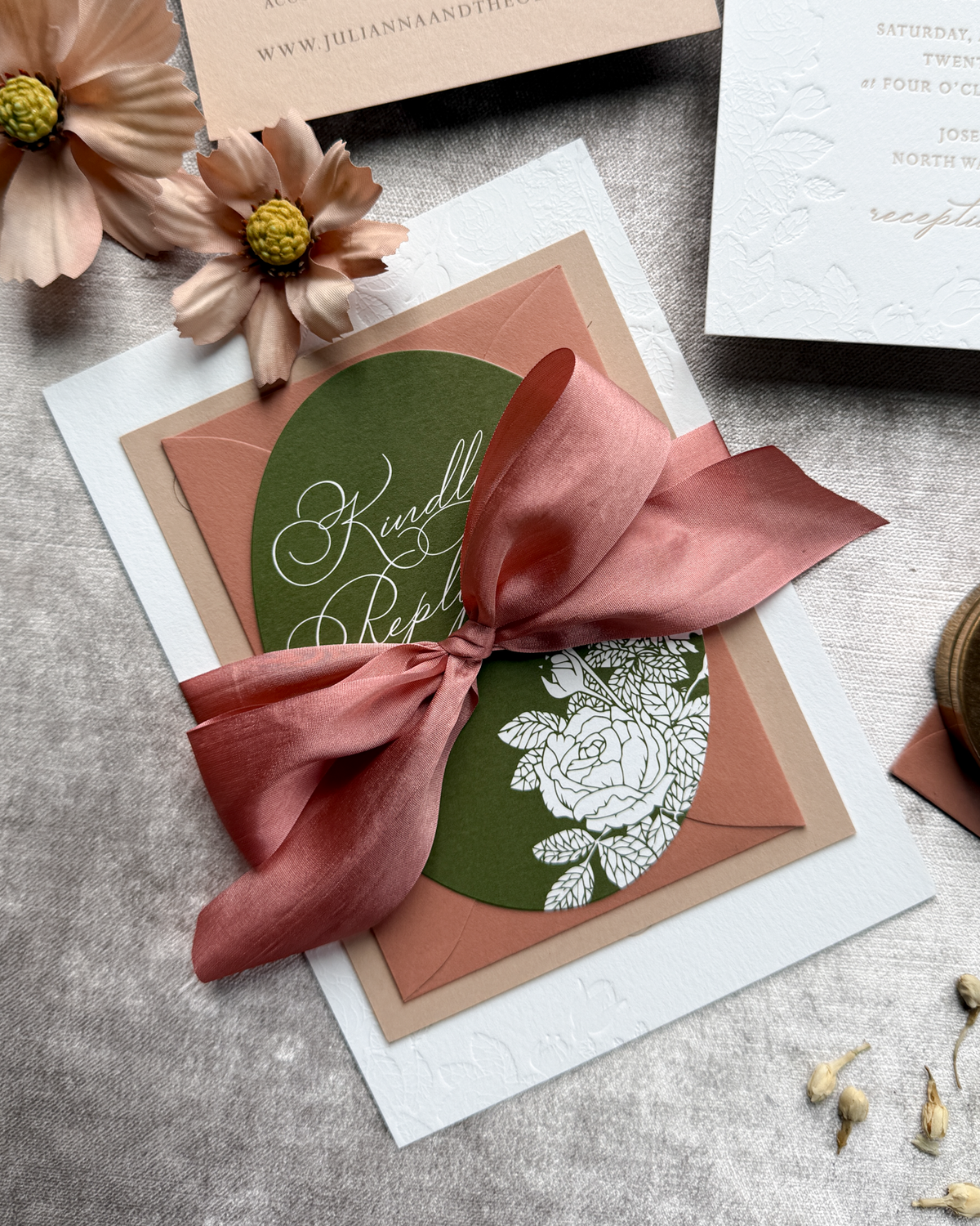 Invitation card with a terra cotta ribbon on a textured surface