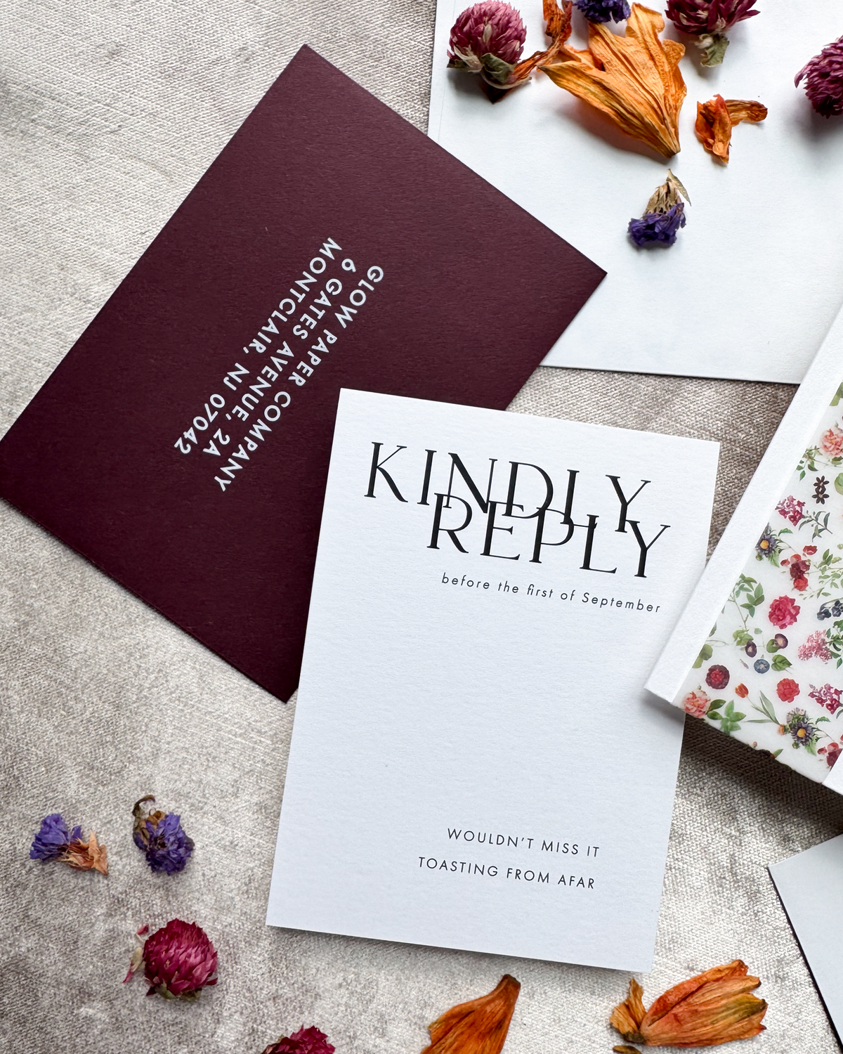 Invitation cards with text and dried flowers on a textured surface