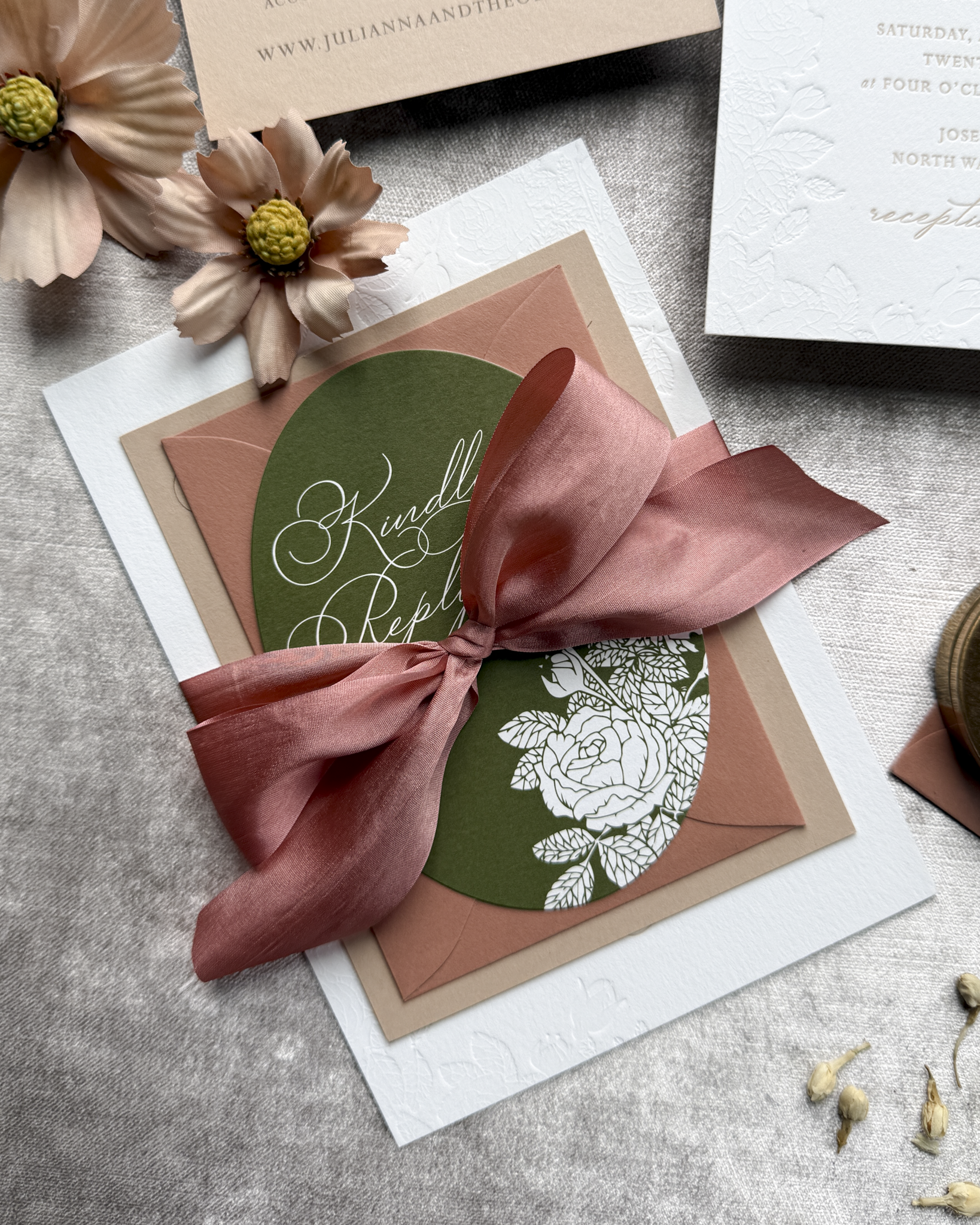 Invitation card with a terra cotta ribbon on a textured surface