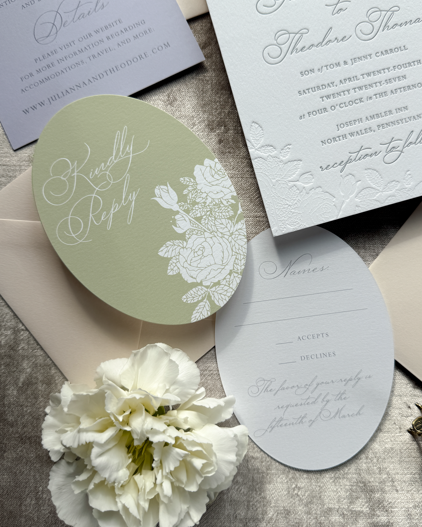 Wedding invitation set with oval die-cut RSVP card and floral design on a textured surface.