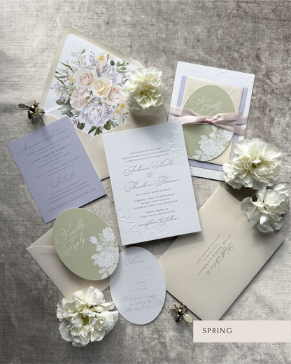 Wedding invitation set with floral designs on a gray surface.