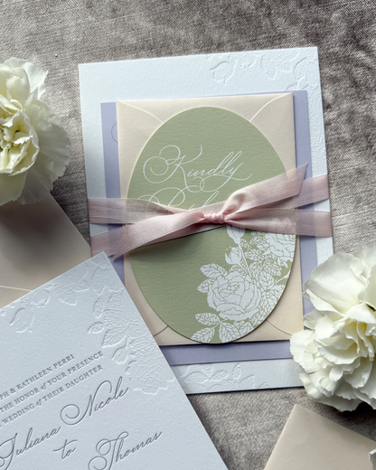 Elegant wedding invitation with floral design and ribbon on a textured surface.