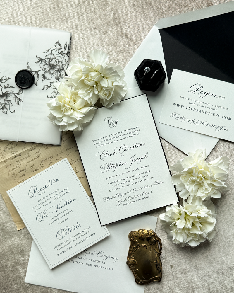 A black and white wedding invitation featuring a tulip vellum wrap and wax seal