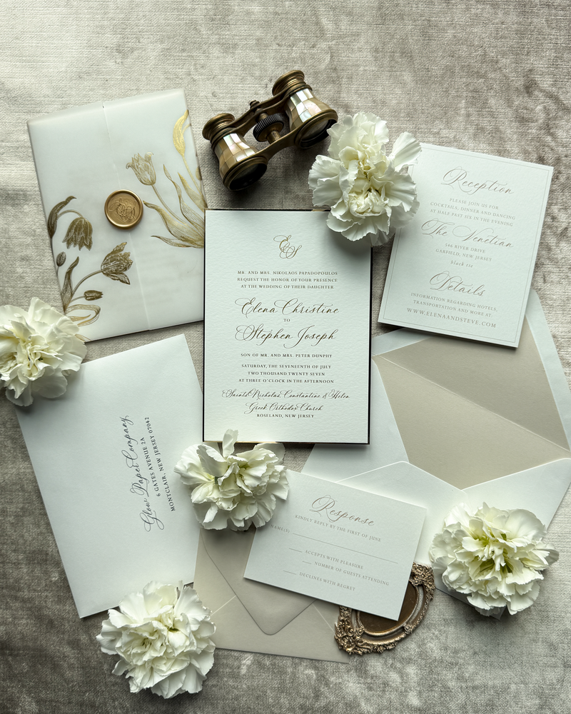 A gold and white wedding invitation featuring a tulip vellum wrap and wax seal