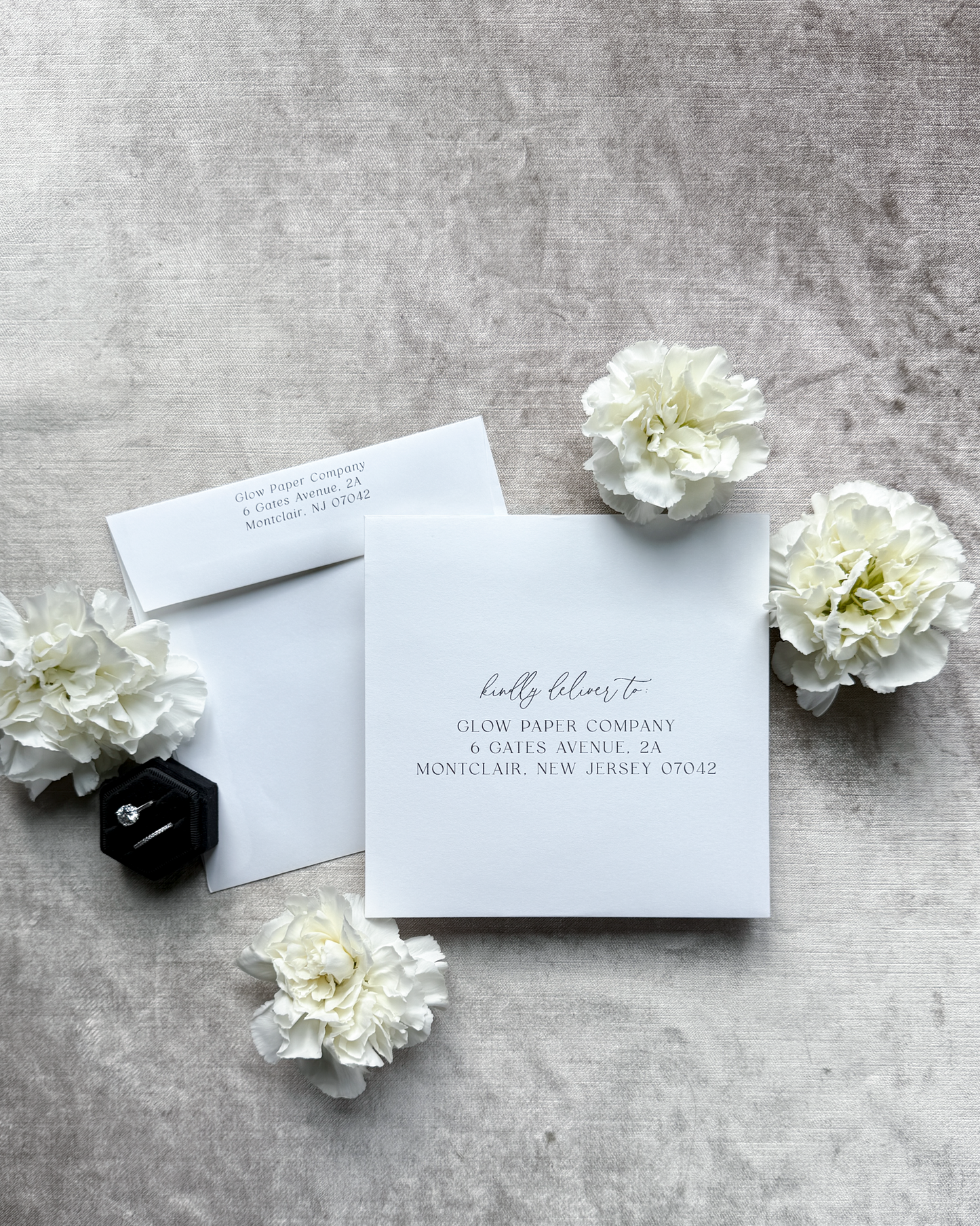 Glow Paper Company stationery set with a card and envelope on a gray surface with white flowers.