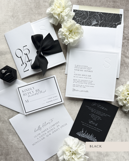 Black and white wedding invitation set with flowers on a textured surface