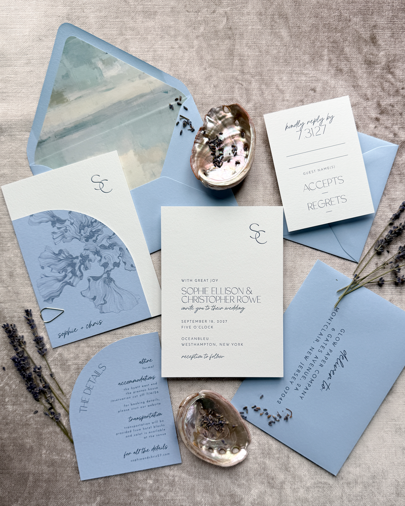 Wedding invitation set with blue and white cards on a textured surface.