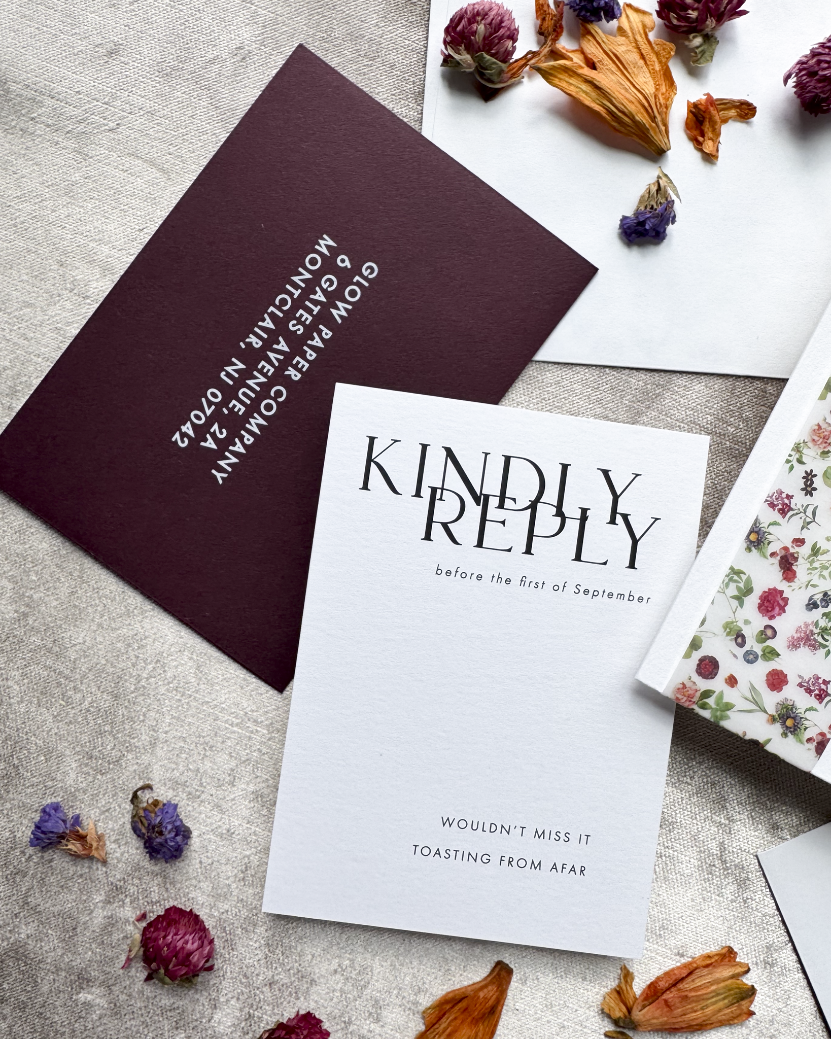 Invitation cards with text and dried flowers on a textured surface